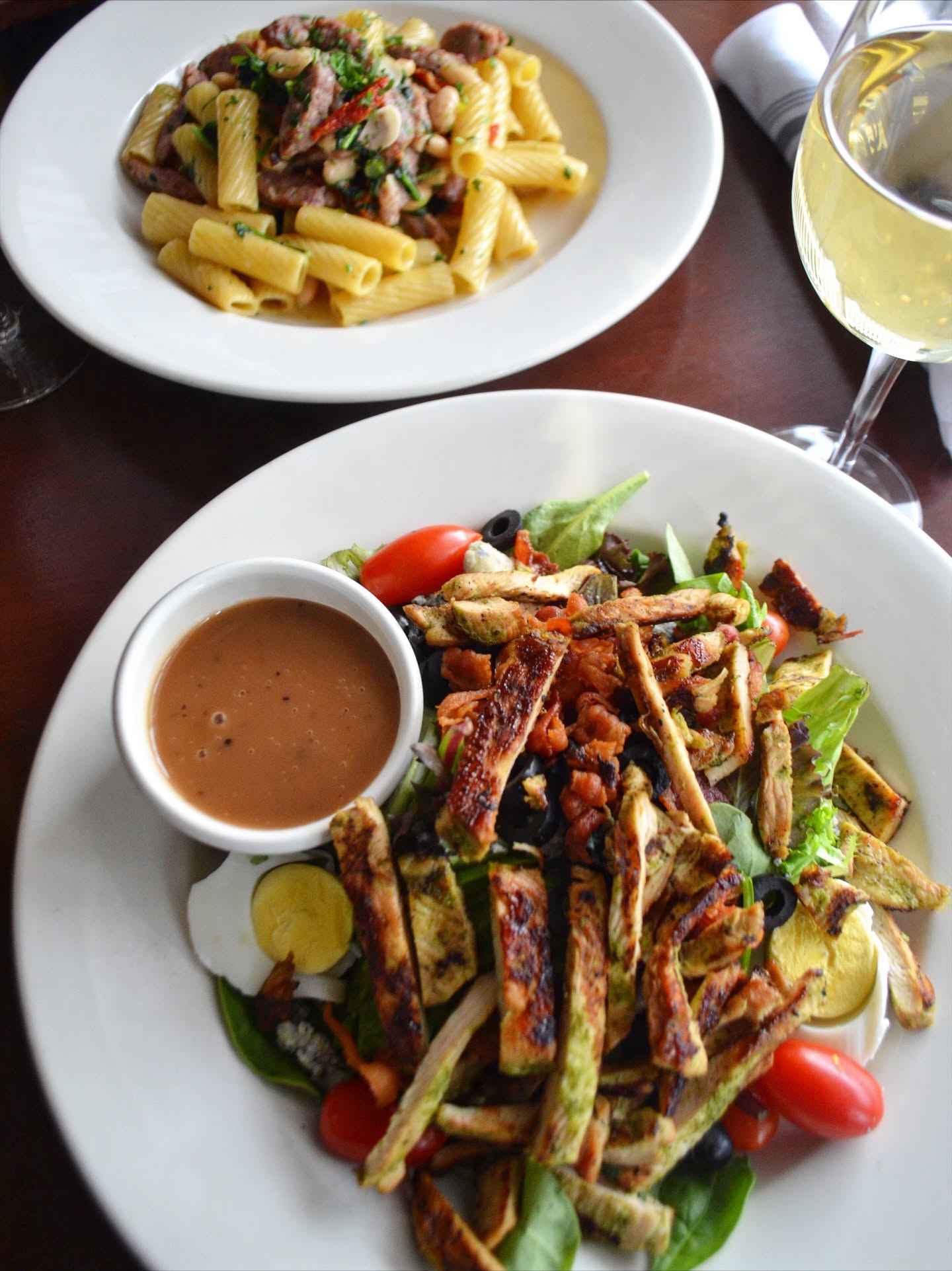 Grilled chicken salad and rigatoni with a glass of white wine